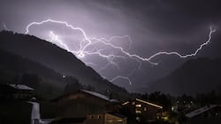 Un éclair ramifié fend le ciel orageux au-dessus de la vallée en direction de Gsteig; photo prise mi-juillet 2026 près de Gstaad (BE).