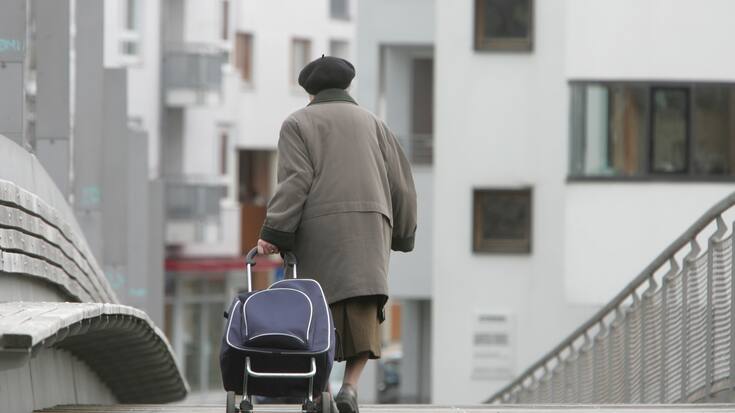 Alte Frau geht mit Einkaufstrolley