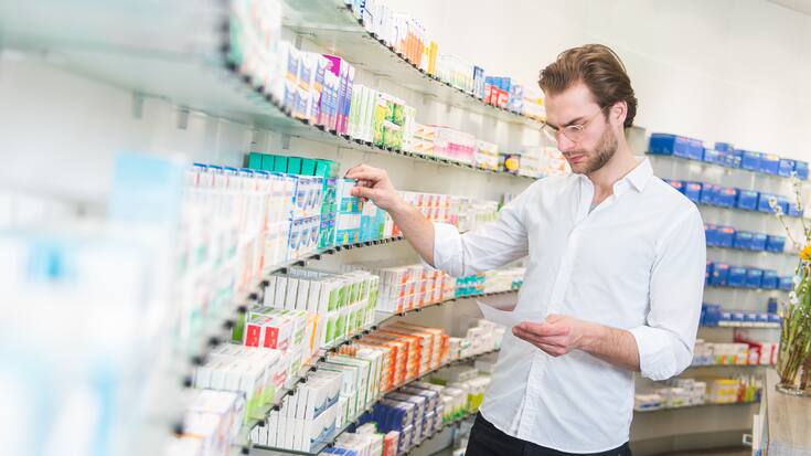 Apotheker sucht Medikamente aus einem Regal