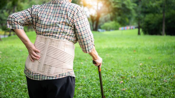 Asian senior woman wearing back support belt for protect her bac
