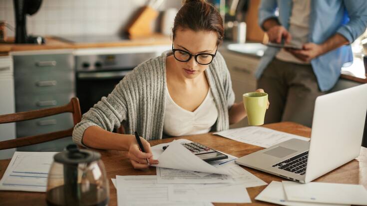 Junge Frau mit Taschenrechner und Laptop