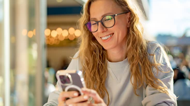 Sitzende Person blickt auf ihr Handy -  Vorsorge per App