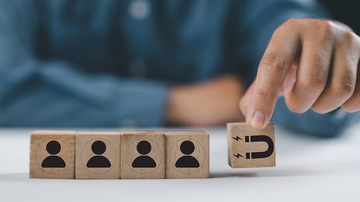 Customer retention concept. Inbound marketing strategy. Attracting potential customers. Hand puts wooden cubes with magnet attracts customer icons on beautiful grey background and copy space. Loyalty