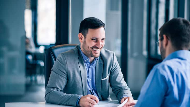 Handsome male client signing document on a meeting with real est