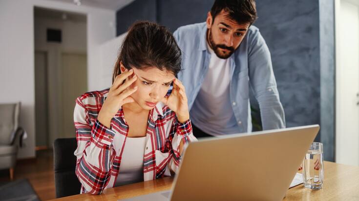 Geschockte Frau mit Mann im Homeoffice, mit Laptop