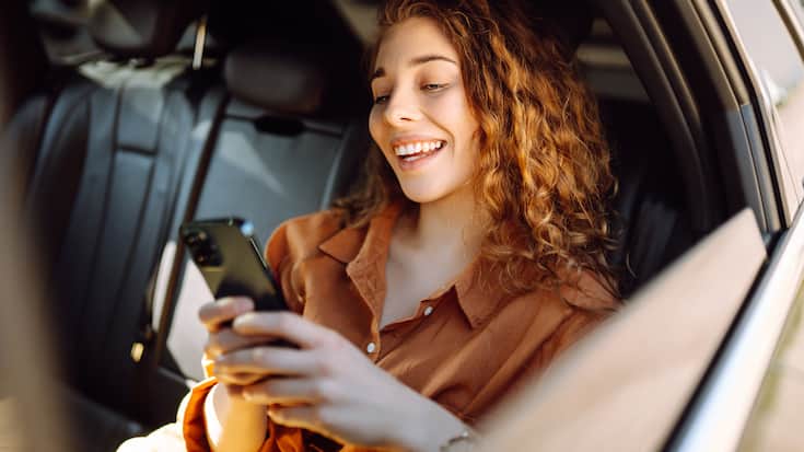 Junge Frau mit Handy im Auto