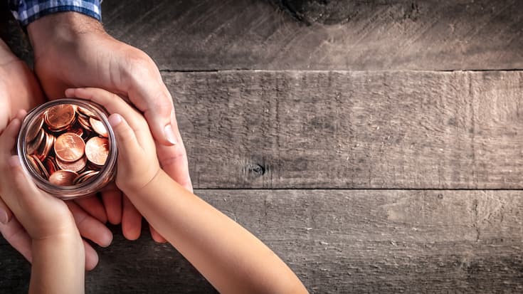 Hands Of Father Giving Jar Of Coins To Child On Wooden Table Background - Inheritance / Parent Providing For Children Concept