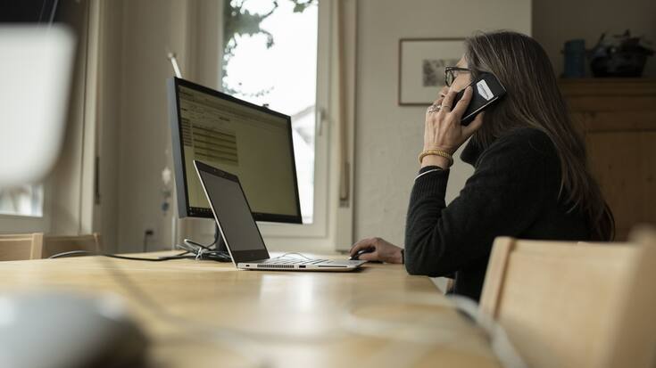 Eine Frau telefoniert an ihrem Arbeitsplatz im Homeoffice