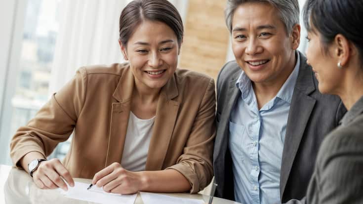 Portrait of happy mature Asian couple signing financial contract at the bank office