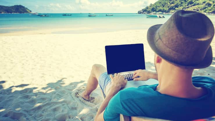 Attractive young man with laptop working on the beach. Freedom, 