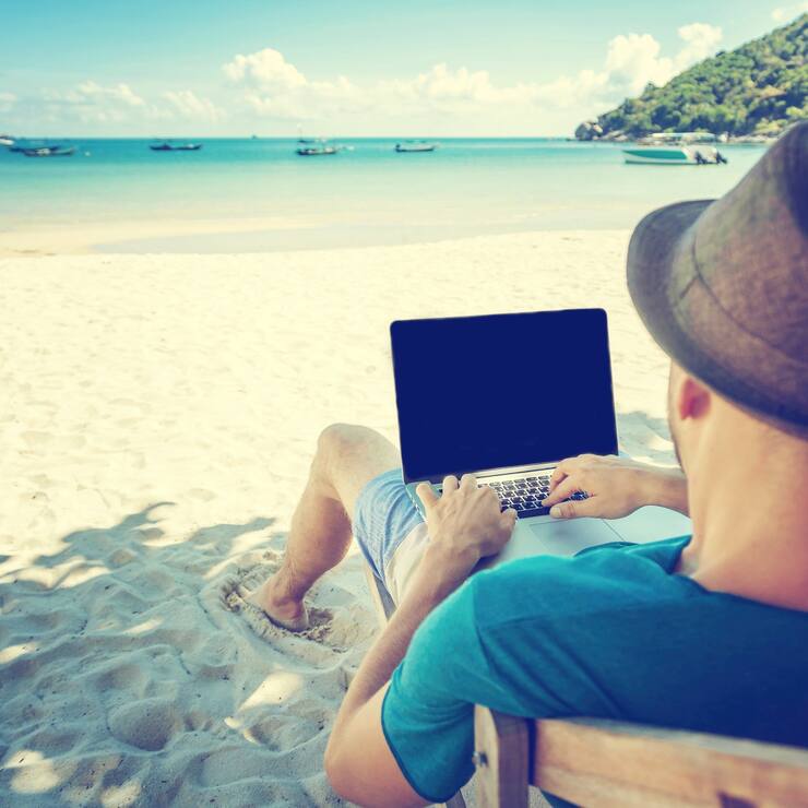 Attractive young man with laptop working on the beach. Freedom, 
