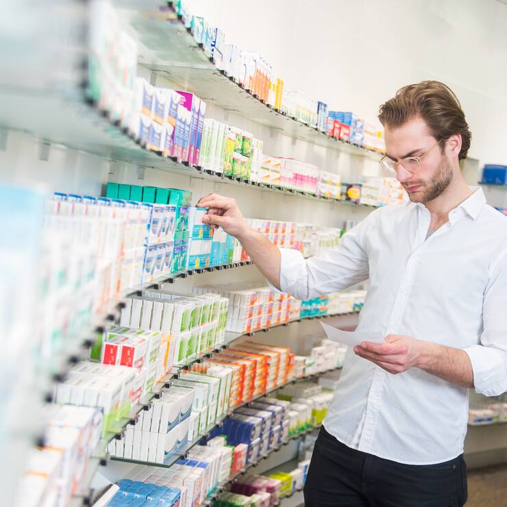 Apotheker sucht Medikamente aus einem Regal