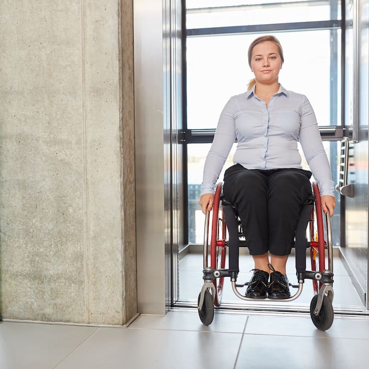 Geschäftsfrau als Rollstuhlfahrerin im Fahrstuhl 