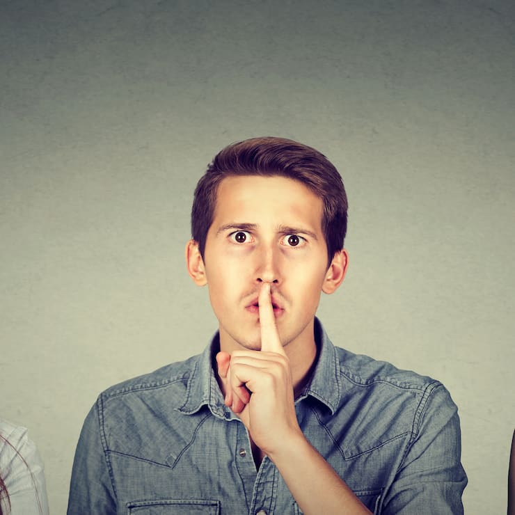 Secretive young people man and two women with finger to lips ges