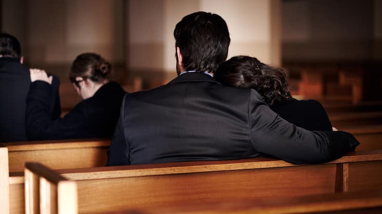 Eine Familie sitzt bei der Beerdigung in der Kirche