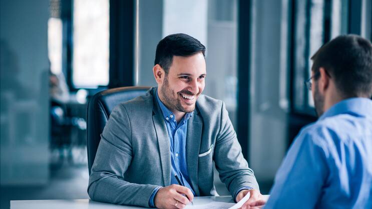 Handsome male client signing document on a meeting with real est