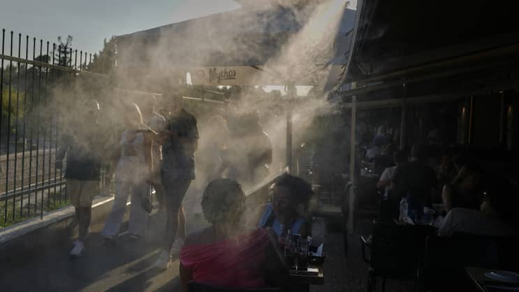 En juillet dernier, des passants passent devant une machine à fumée pour se rafraîchir lors d'une journée caniculaire dans le quartier Monastiraki d'Athènes.